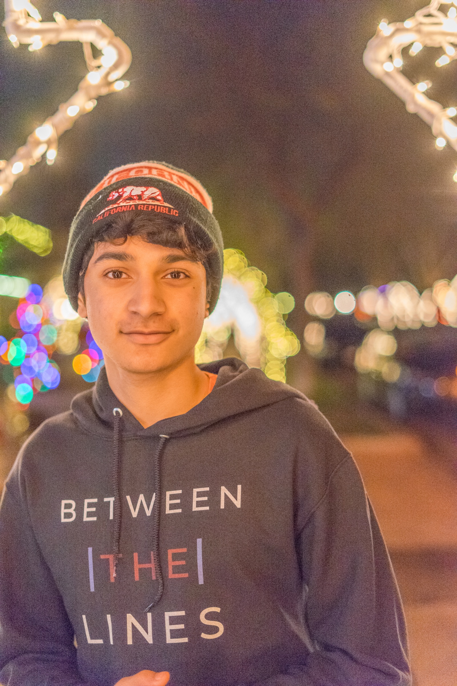 Portrait of a person in a beanie and hoodie surrounded by colorful lights