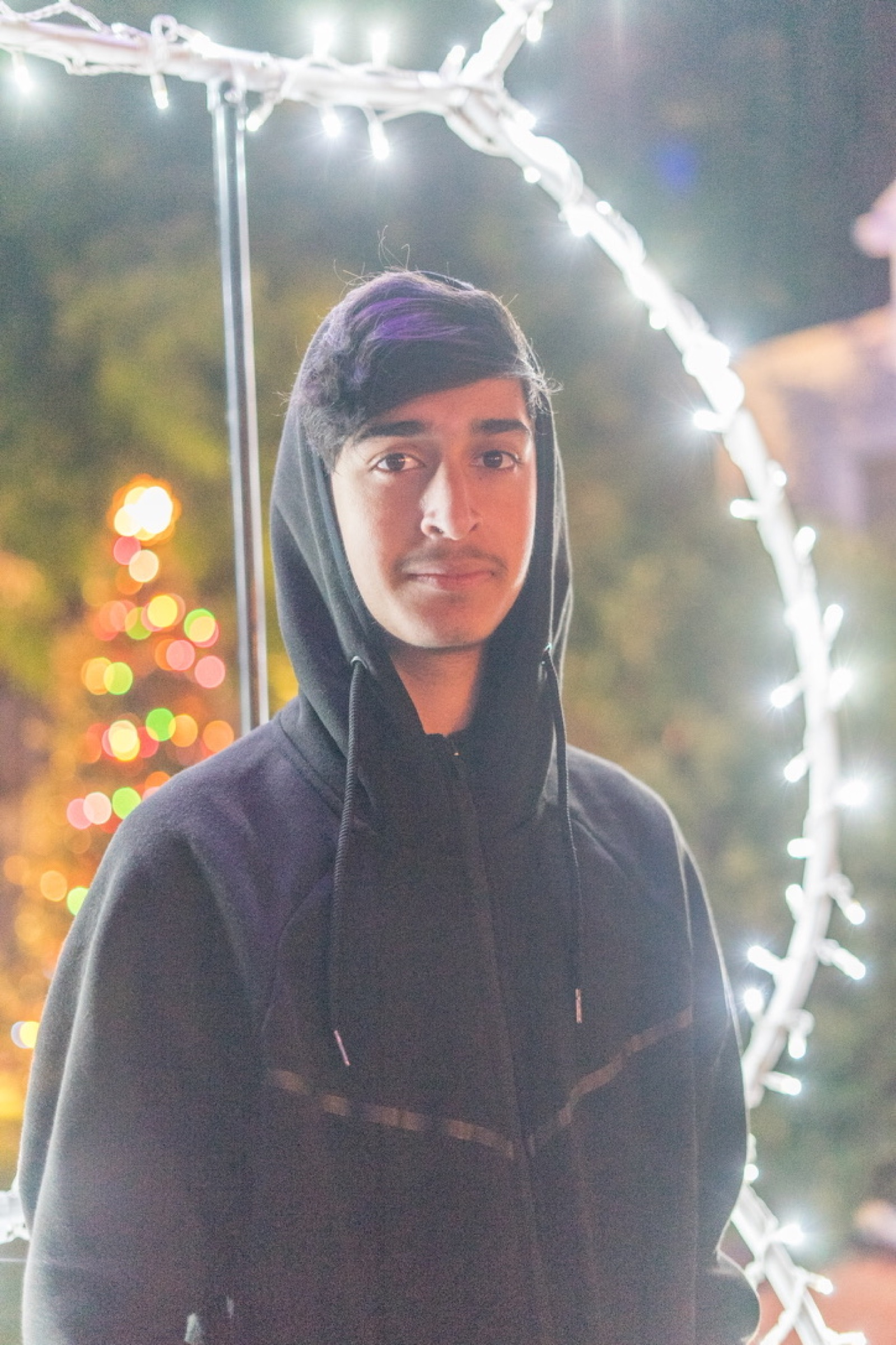 Portrait of a person in a hoodie surrounded by string lights