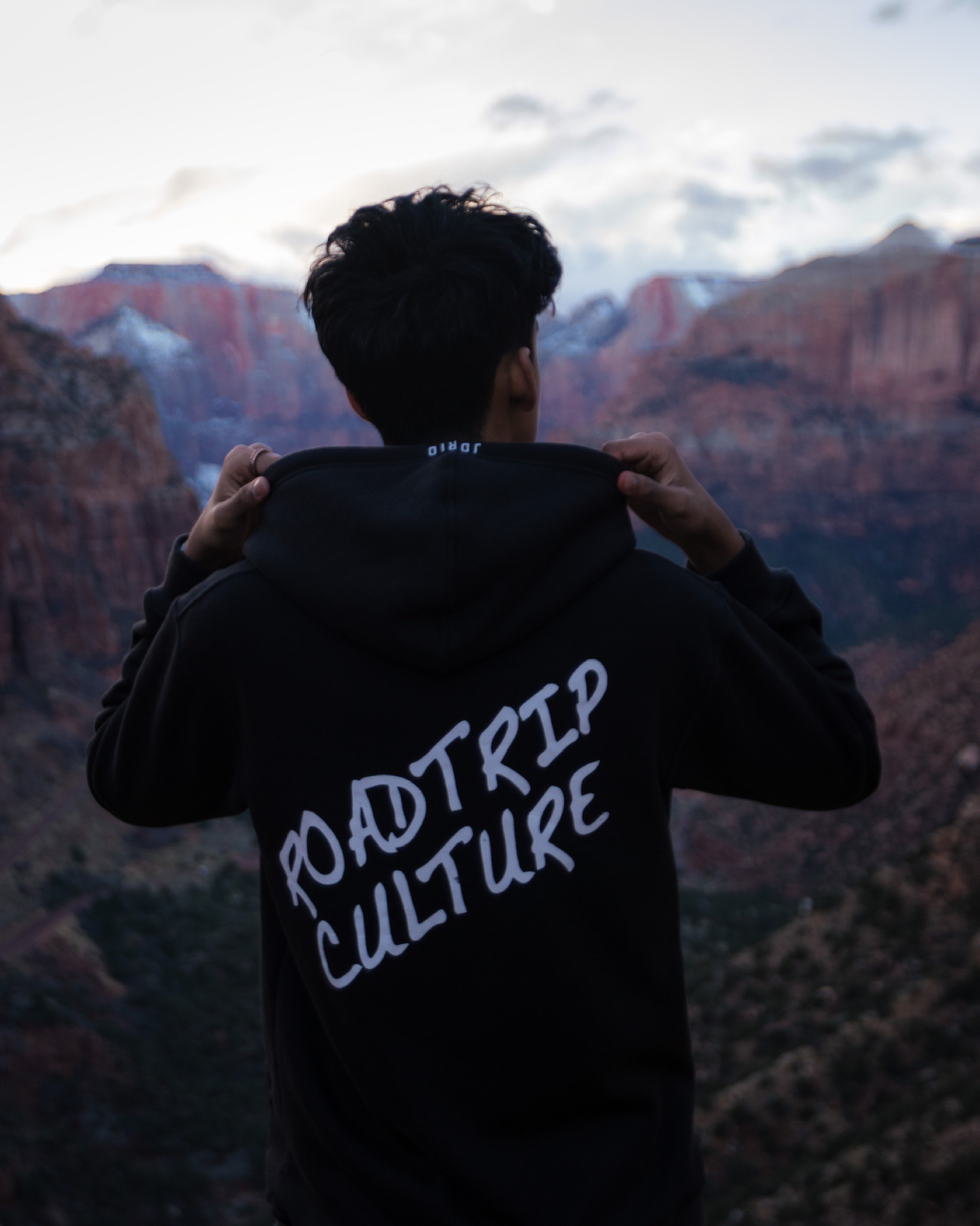 A person holding up a Roadtrip Culture hoodie in front of red canyon walls