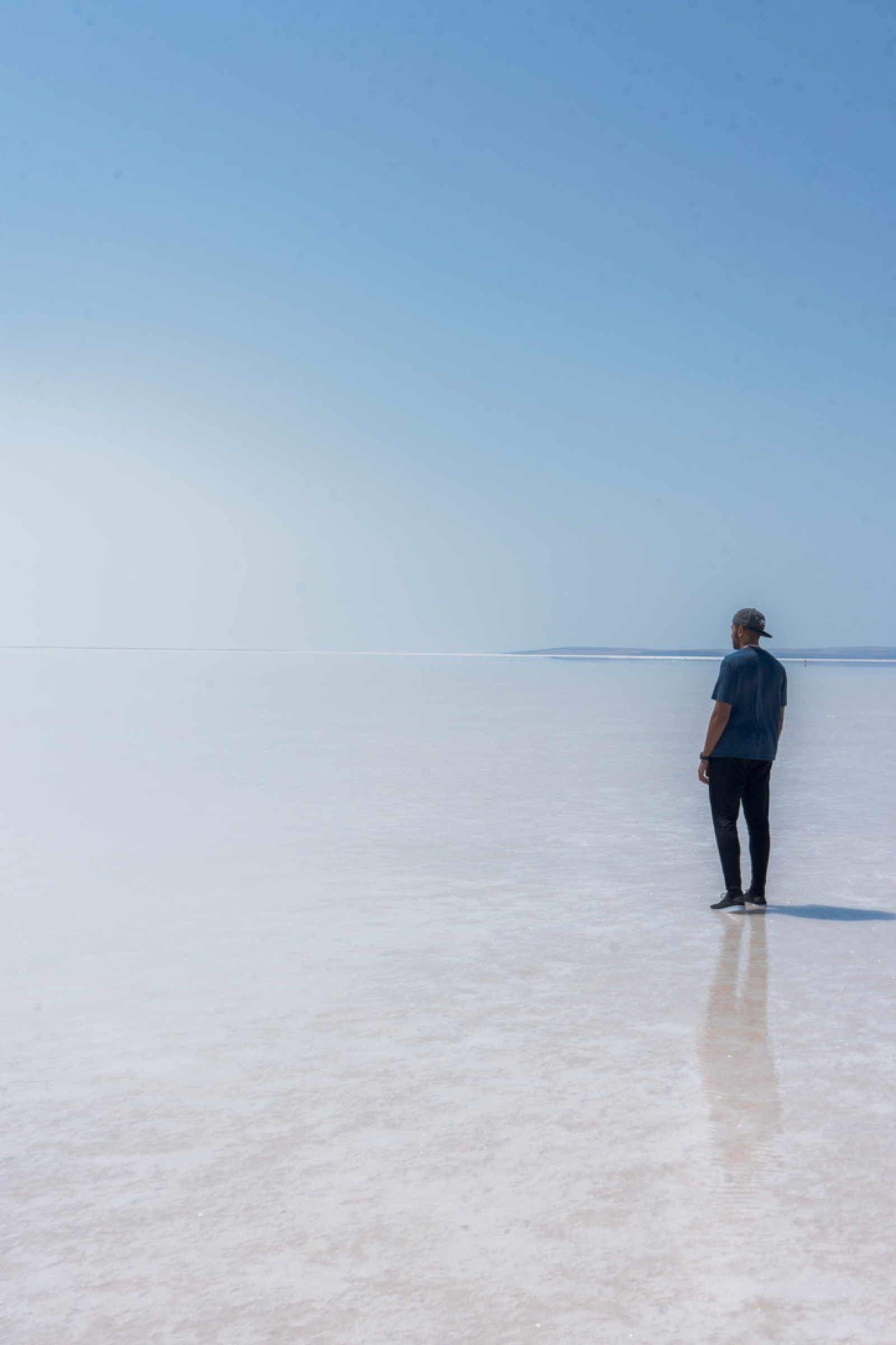 A solitary person standing in a vast reflective salt lake