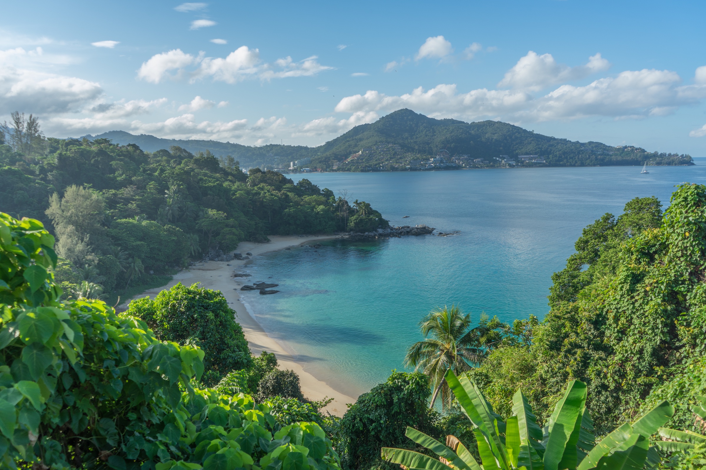 Tropical bay with clear blue water surrounded by lush green hills